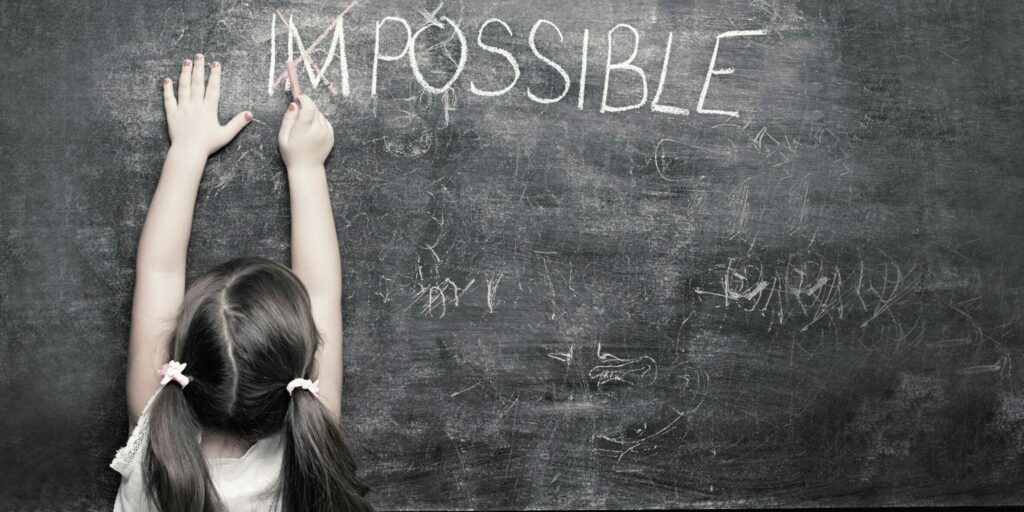 Cute,Little,Girl,Putting,A,Cross,Over,Impossible,On,Blackboard