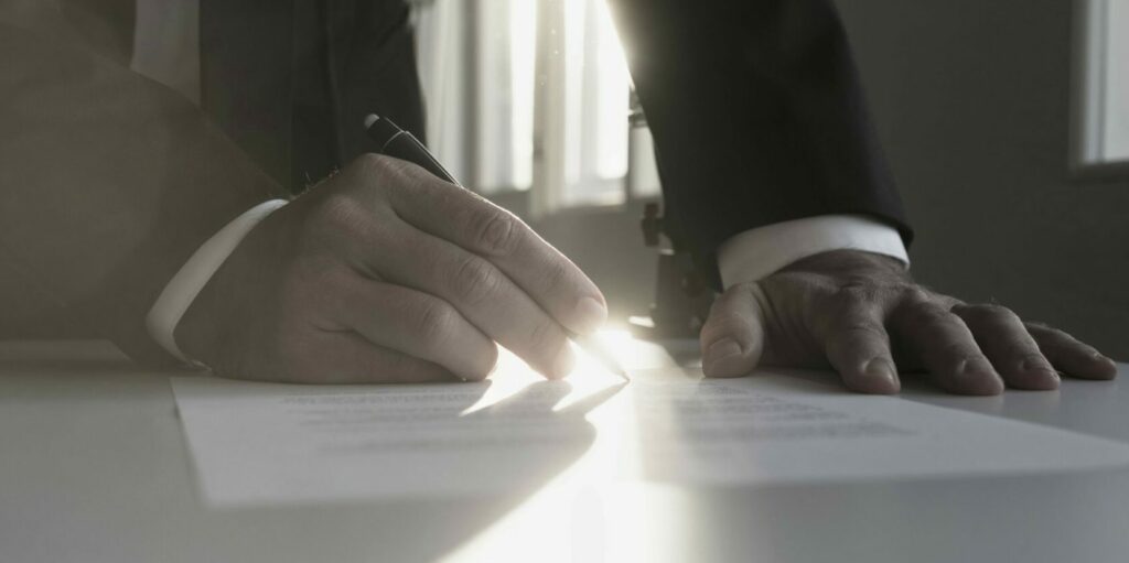 Panorama,View,Of,Businessman,In,A,Shadowy,Office,Signing,Contract